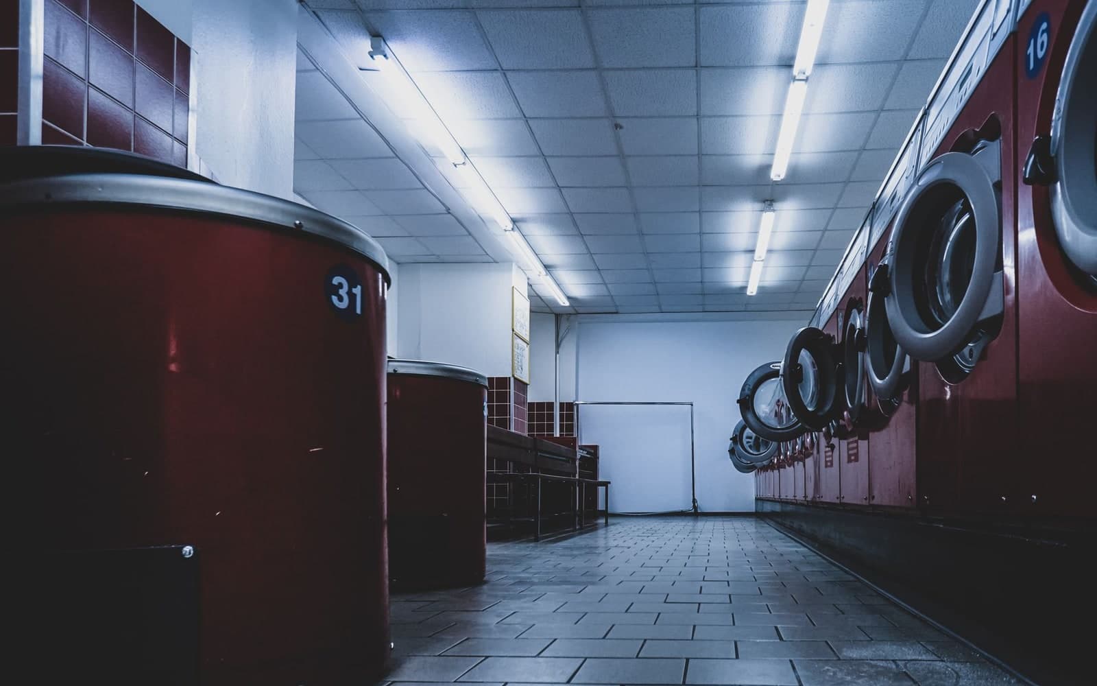 Row of red front-loader washing machines in a self-service laundromat