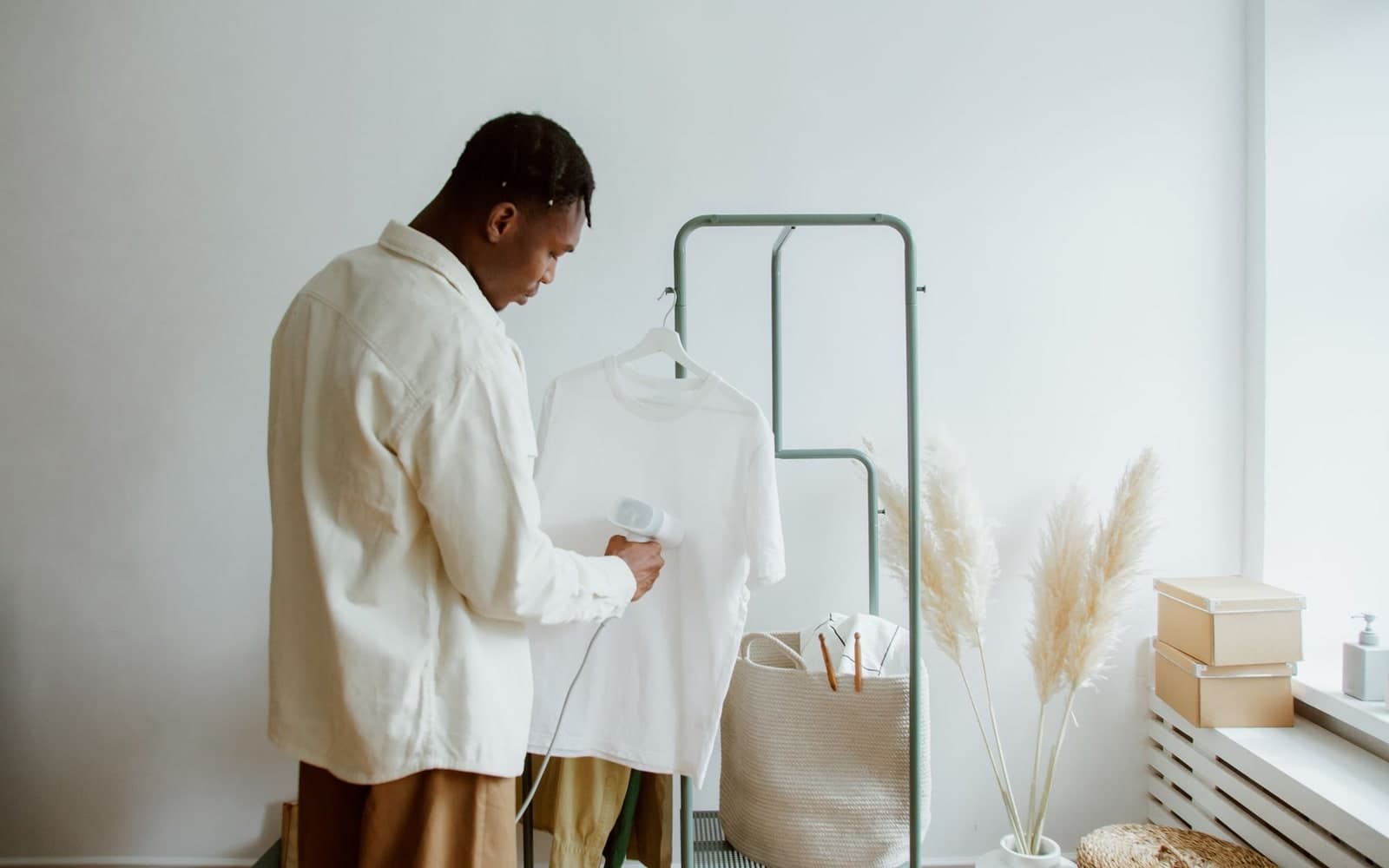 Man steaming a white t-shirt hanging on a clothing rack