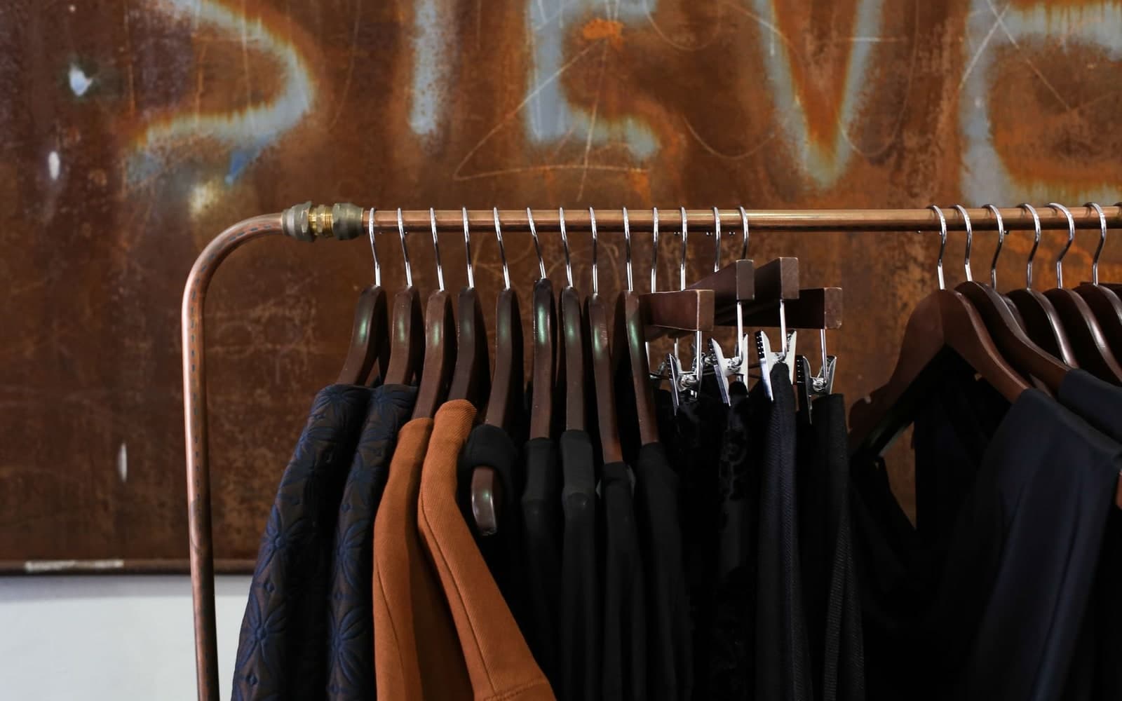 Garments on wooden hangers on a metal rack in a boutique