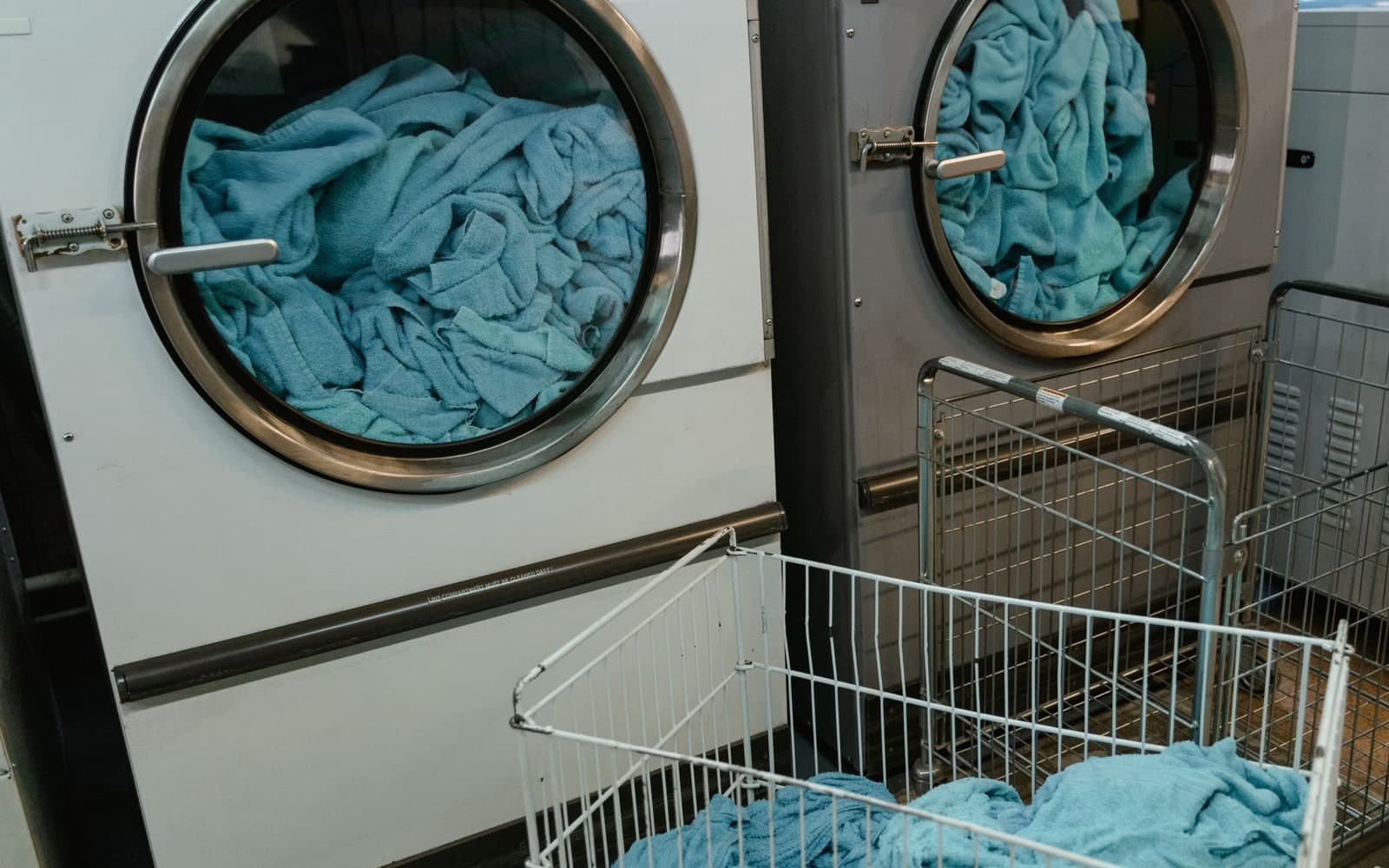 Commercial washing machines loaded with blue textiles in a laundry facility