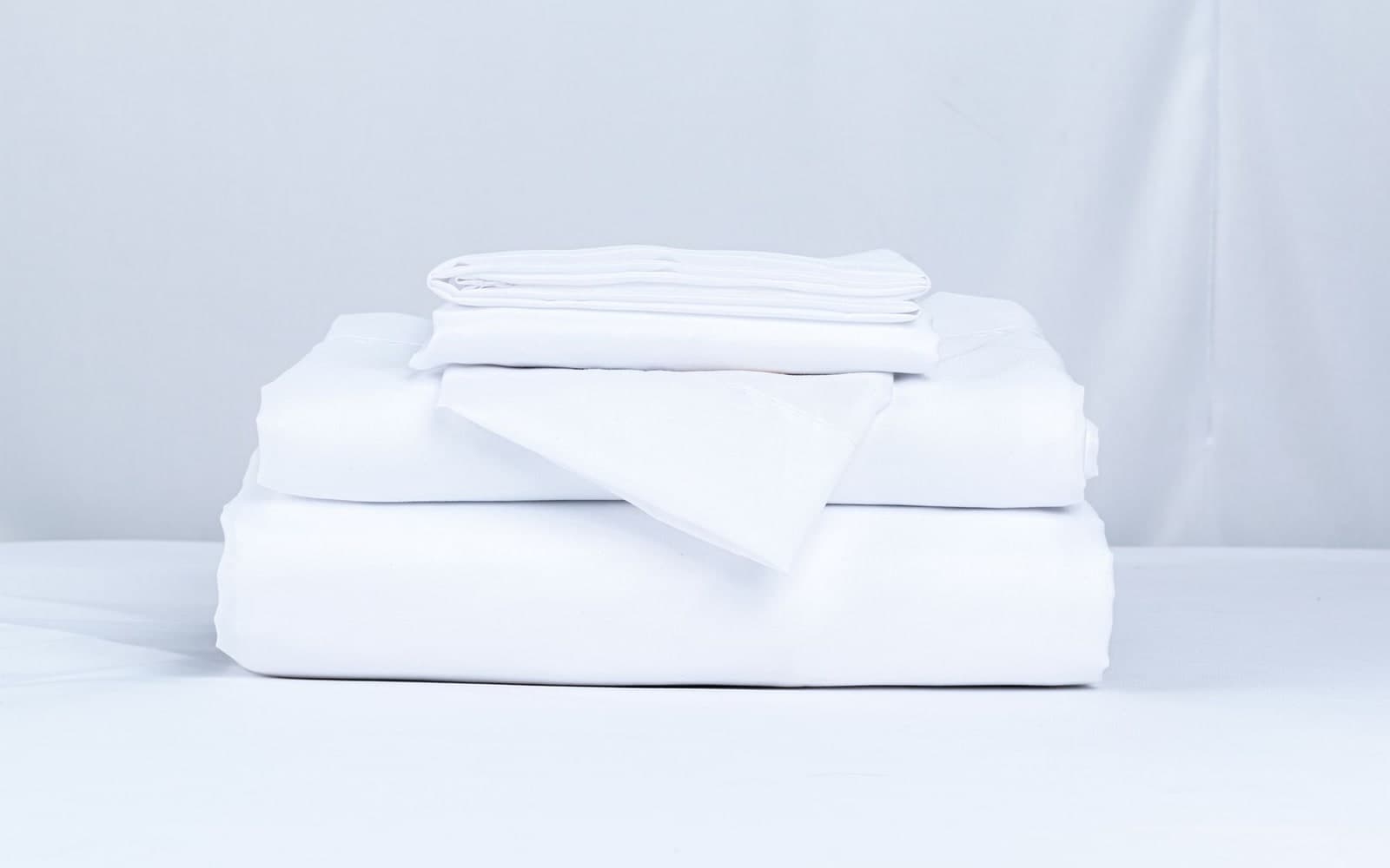 Neatly folded stack of crisp white hotel bed linen