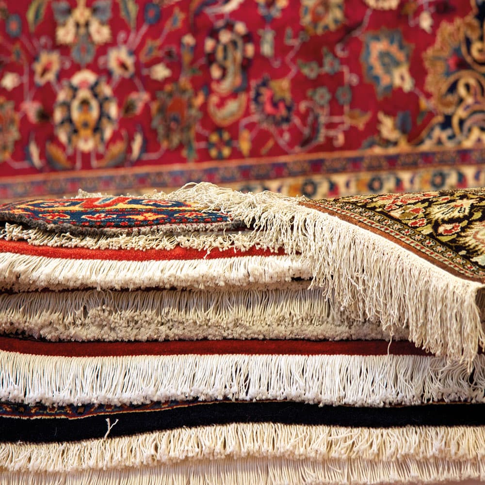 A patterned rug being handled for solvent cleaning