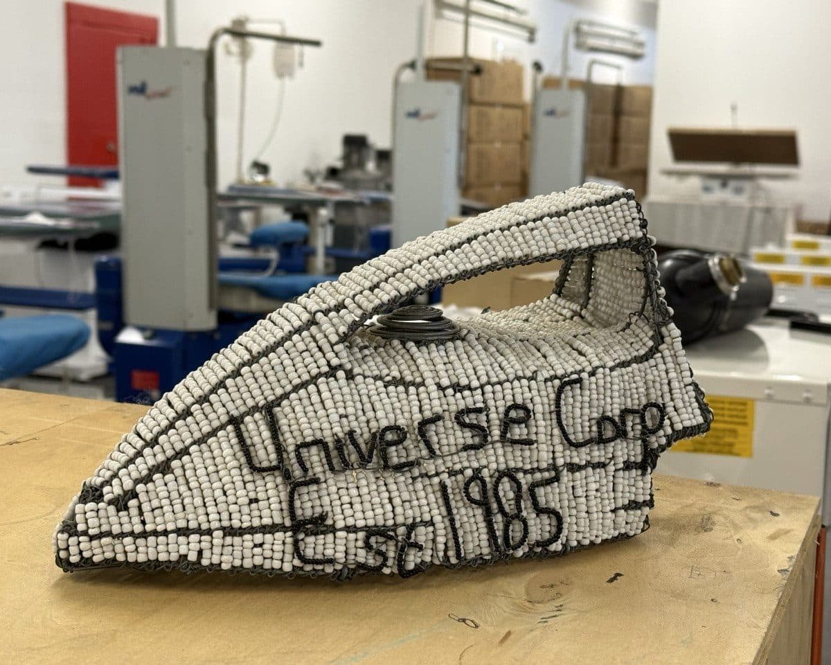 Hand-beaded wire-and-glass model of a steam iron reading Universe Corp Est 1985